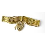A 9ct gold six bar gate bracelet united with a 9ct gold heart-shaped padlock clasp,