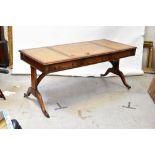 A reproduction mahogany writing table set with three gilt tooled tan leather panels above three