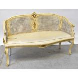 A cream painted and gilt-heightened bergère caned two-seater settee,