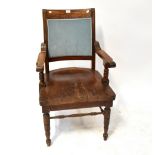An early 20th century oak open arm elbow chair with saddle seat,