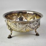 A Georgian hallmarked silver bowl with swag and grape repoussé decoration, to three hooped supports,