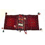 An Afghan Beshir hand knotted donkey bag with central panel of nine medallions within stepped