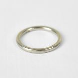 A platinum wedding band with etched feathered decoration to the flat sides, stamped 'Plat', size T,