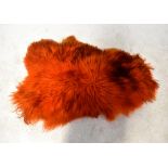 A vintage c1960s vivid orange and black sheepskin rug, length approx 110cm.