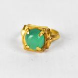 A yellow metal dress ring set with cabochon chrysoprase in a claw setting,
