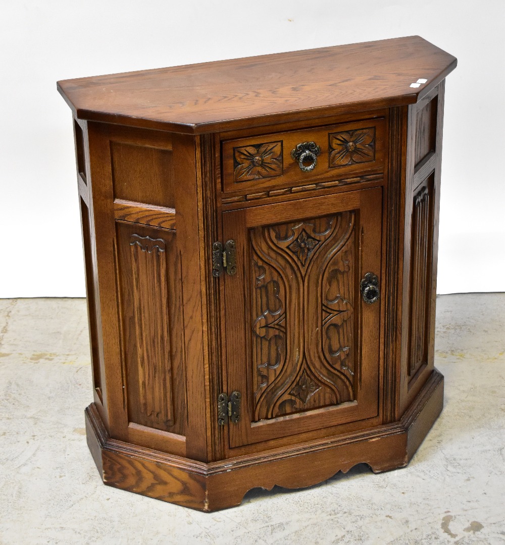 A reproduction oak credence cupboard, the shaped top above single drawer with carved detail,