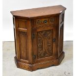 A reproduction oak credence cupboard, the shaped top above single drawer with carved detail,