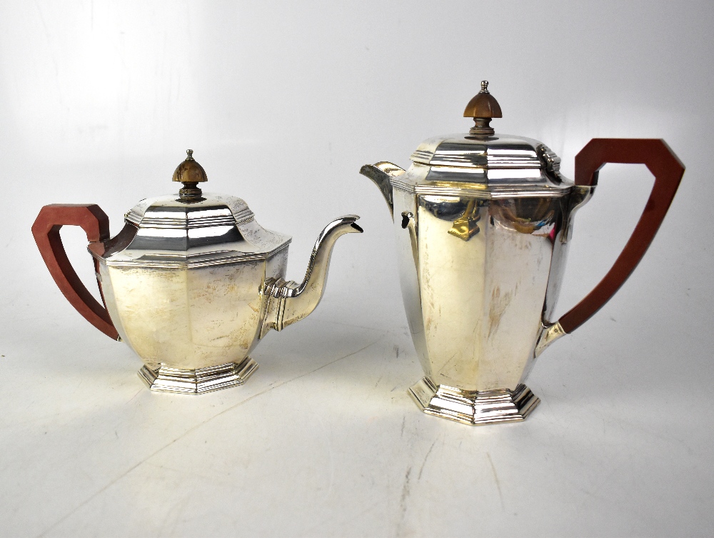 A George V hallmarked silver teapot and matching hot water pot of octagonal form,