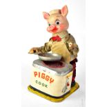 A vintage Japanese tinplate automaton of a pig as a chef in front of a stove with a frying pan,