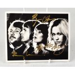 ABBA; a black and white photo card bearing the signatures of the four band members in gold pen.