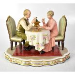 CAPODIMONTE; a figure group of a couple sat at a dining table with Champagne and cake,