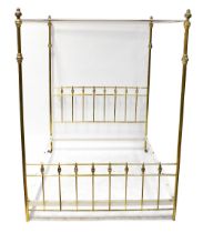 A brass four-poster double bed with reeded columns and white painted metal connecting rails,