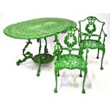 A green painted aluminium garden dining set comprising an oval table with pierced floral scrollwork