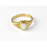 A 9ct gold opal ring, the raised bezel set opal with greens, blues and red, in a wrythen mount,