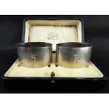 A cased set of two initialled hallmarked silver napkin rings, one inscribed with the letter 'S',