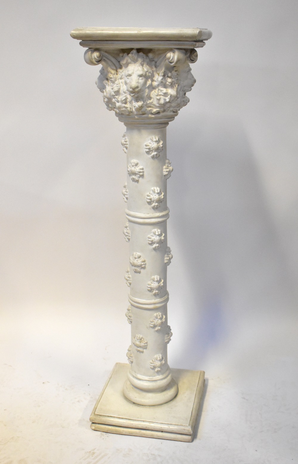 A large plaster column/plant stand, with square top above lion mask with brackets and floral fill,