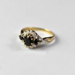 A 9ct gold sapphire and diamond ring, the principal oval sapphire flanked by two tiny sapphires,