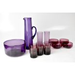 A mid-20th century collection of purple glassware, comprising a tall jug, highball glasses, balls,