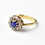 A yellow gold ladies' dress ring, floral set with central blue stone and white stone surround,