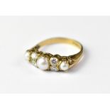 A 9ct gold dress ring with principal seed pearl flanked by two small white stones either side,