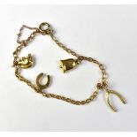 A 9ct gold dainty charm bracelet with four charms, comprising wishbone, horseshoe,