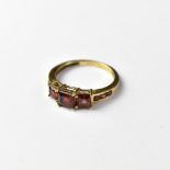 A 9ct gold garnet ring, with square cut claw set garnet flanked by two smaller square garnets,