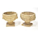 A pair of composite garden urns with swag decoration, raised on a square section base, height 34cm,