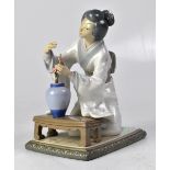 LLADRÓ; a figure of a kneeling geisha arranging flowers in a vase, height 20cm (af).