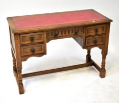 A reproduction oak five-drawer desk, the top with gilt tooled red leather inset panel,