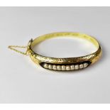 A late 19th century hinged bracelet with central line of ten inset seed pearls within a black