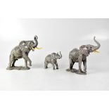 A family of three elephants, parents on a stylised rocky oval plinth base,