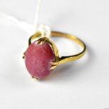 An 18ct gold ring with a four-claw set red stone cabochon, size R, approx 4.8g.