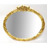 A gilt framed oval wall mirror, the frame with stylised iris motifs, 110 x 126cm.