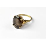 A 9ct gold smoky quartz dress ring, the oval cut stone in a four-claw mount,