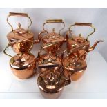 Seven 19th century copper kettles with tubular handles, acorn finials and fishtail joints,