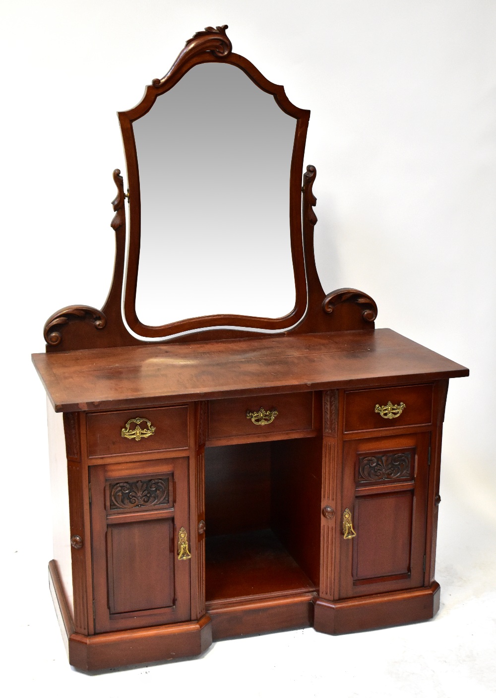 An Edwardian mahogany dressing table with integral swing shield-shaped toilet mirror to the top,