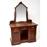 An Edwardian mahogany dressing table with integral swing shield-shaped toilet mirror to the top,