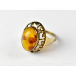 A 9ct gold amber ring, the bezel set oval amber stone in a cage mount, size M, approx 2.4g.