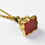 A 19th century carnelian inset stone fancy watch fob seal mounted on a 9ct gold necklace