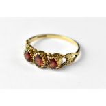 A 9ct gold ring with three bezel set garnets and open love heart shoulders, size S, approx 2.3g.