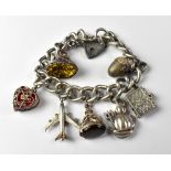 A silver charm bracelet with seven charms comprising an acorn which opens to reveal a lion's head,