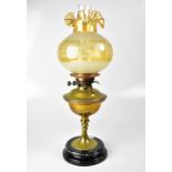 A brass oil lamp with chimney and globular acid etched shade, above brass reservoir and stem,