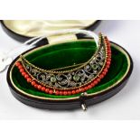 A large gold crescent brooch with an open floral body with three bezel set small emeralds,