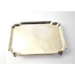 A George VI hallmarked silver tray of canted rectangular form, raised on three scroll feet,