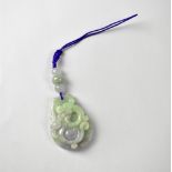 A green and lavender multicoloured oval jade pendant carved with a dragon, suspended by three beads,