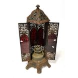A Veritas paraffin stove in cast iron with pierced lattice and floral decoration and red glass