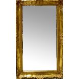 A gilt-framed wall mirror of rectangular form, with bevelled plate, in a Rococo-style surround,