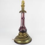 A cut glass flashed cranberry glass table lamp with brass top and acanthus leaf apron,