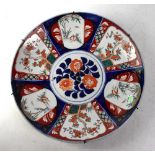 A 19th century Japanese Imari charger with central floral panel in a surround of panels depicting