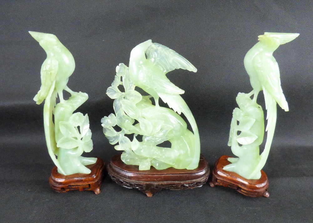 A pair of Oriental jade-style exotic birds on flowering branches, on wooden stands, height 21cm,